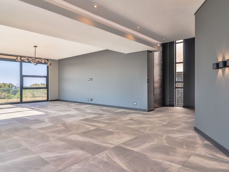 Spacious, modern living area featuring large format floor tiles, recessed lighting, and expansive glass sliding doors that provide abundant natural light and outdoor views.
