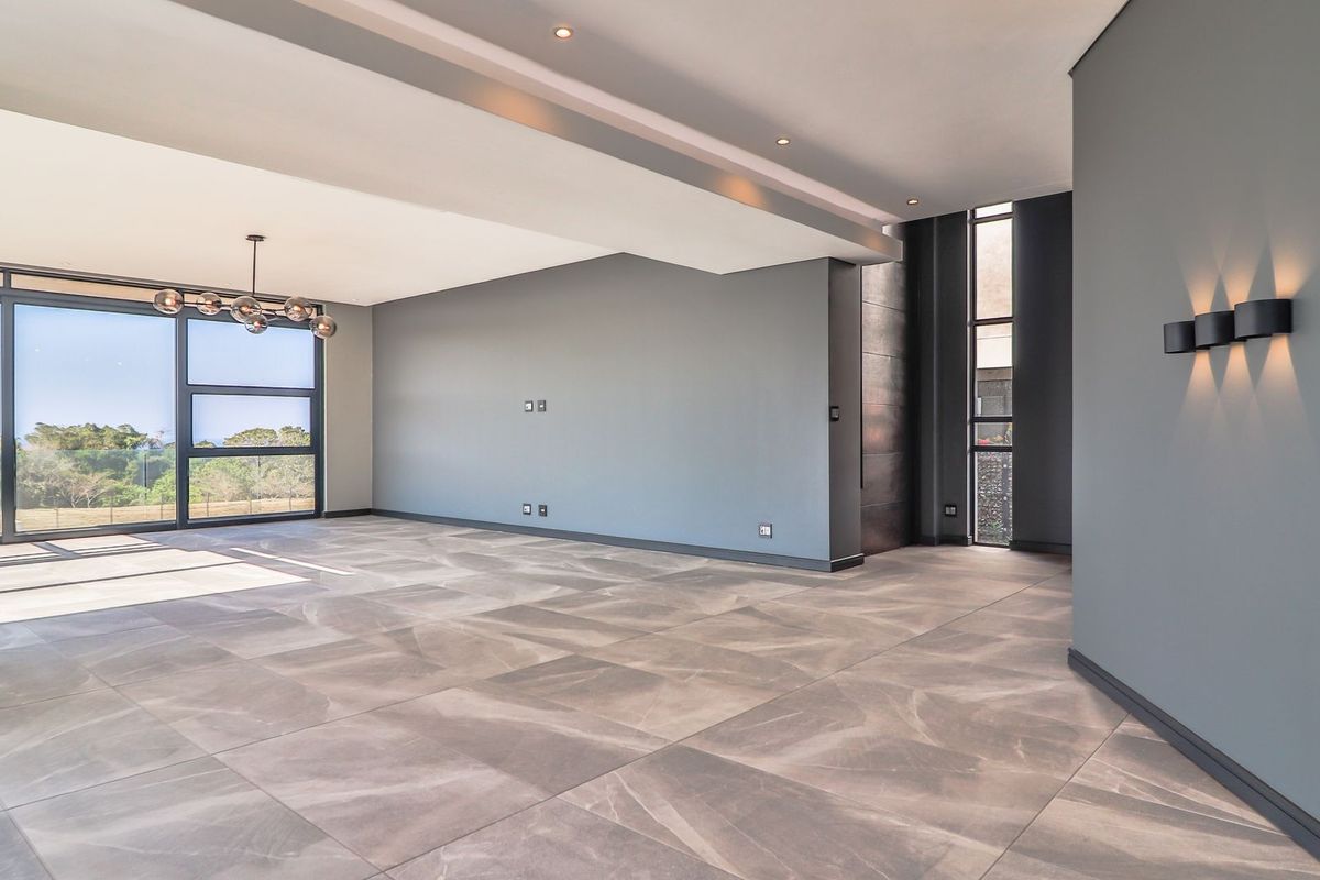 Spacious, modern living area featuring large format floor tiles, recessed lighting, and expansive glass sliding doors that provide abundant natural light and outdoor views.