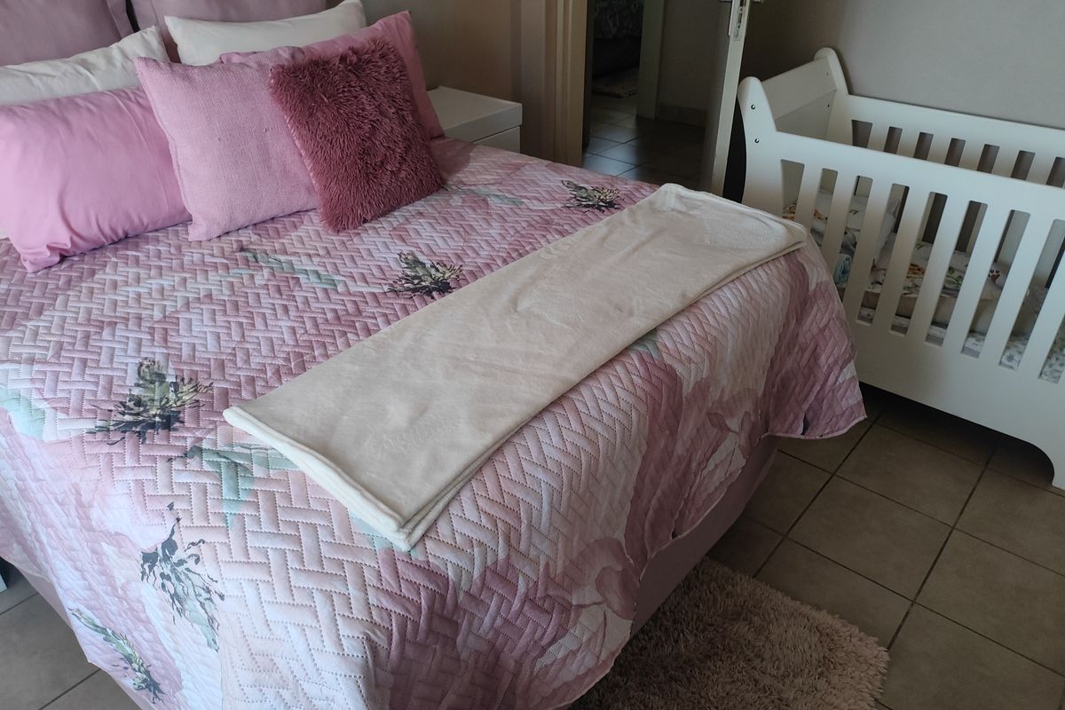A bedroom featuring tiled flooring and a doorway leading to an adjacent space.