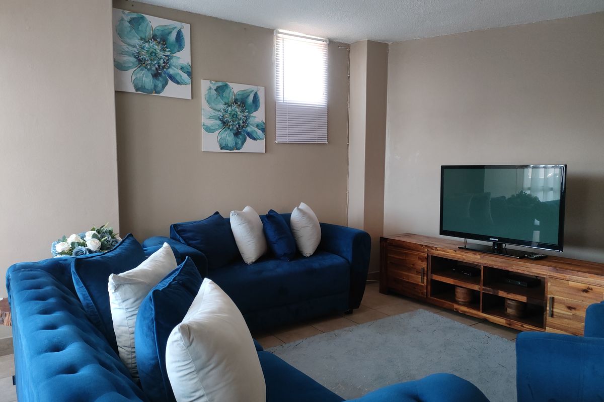 A comfortable living room featuring tiled flooring and a small window with fitted blinds, providing a functional and inviting space for relaxation.