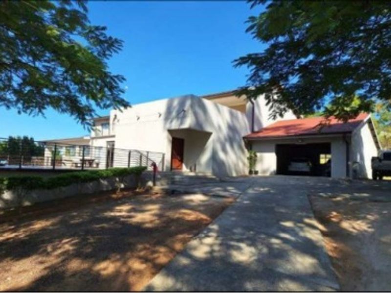 Front elevation of a farm property featuring a concrete driveway, attached garage, and a multi-level structure with a tiled roof.