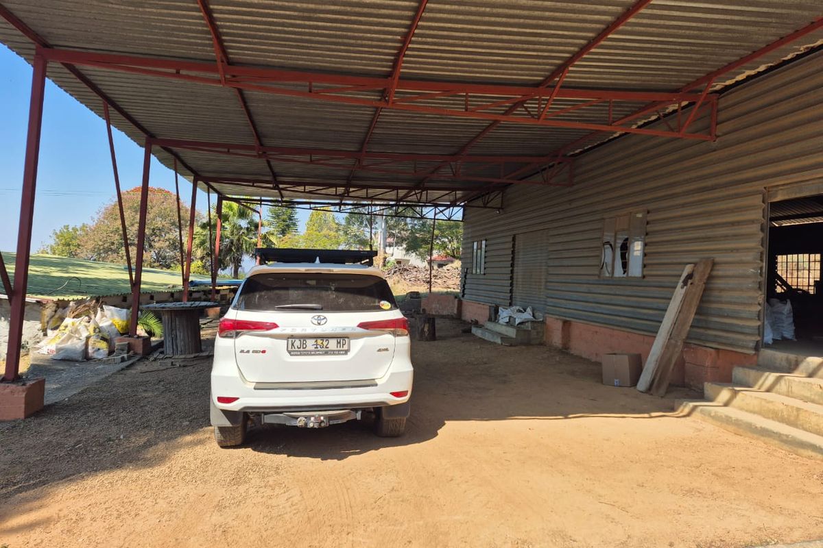 A large covered outdoor utility area featuring a corrugated metal roof and wall cladding, suitable for storage or farm equipment shelter.
