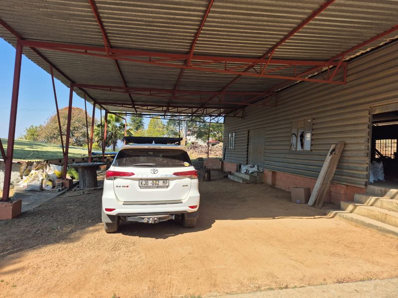 A large covered outdoor utility area featuring a corrugated metal roof and wall cladding, suitable for storage or farm equipment shelter.