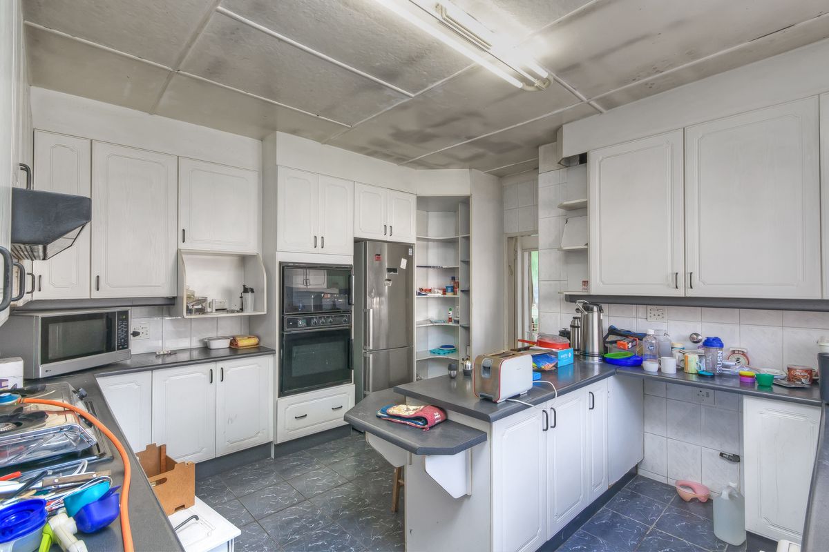 A dated kitchen featuring white cabinetry, built-in oven, and dark countertops, requiring cosmetic updates to modernize the space.
