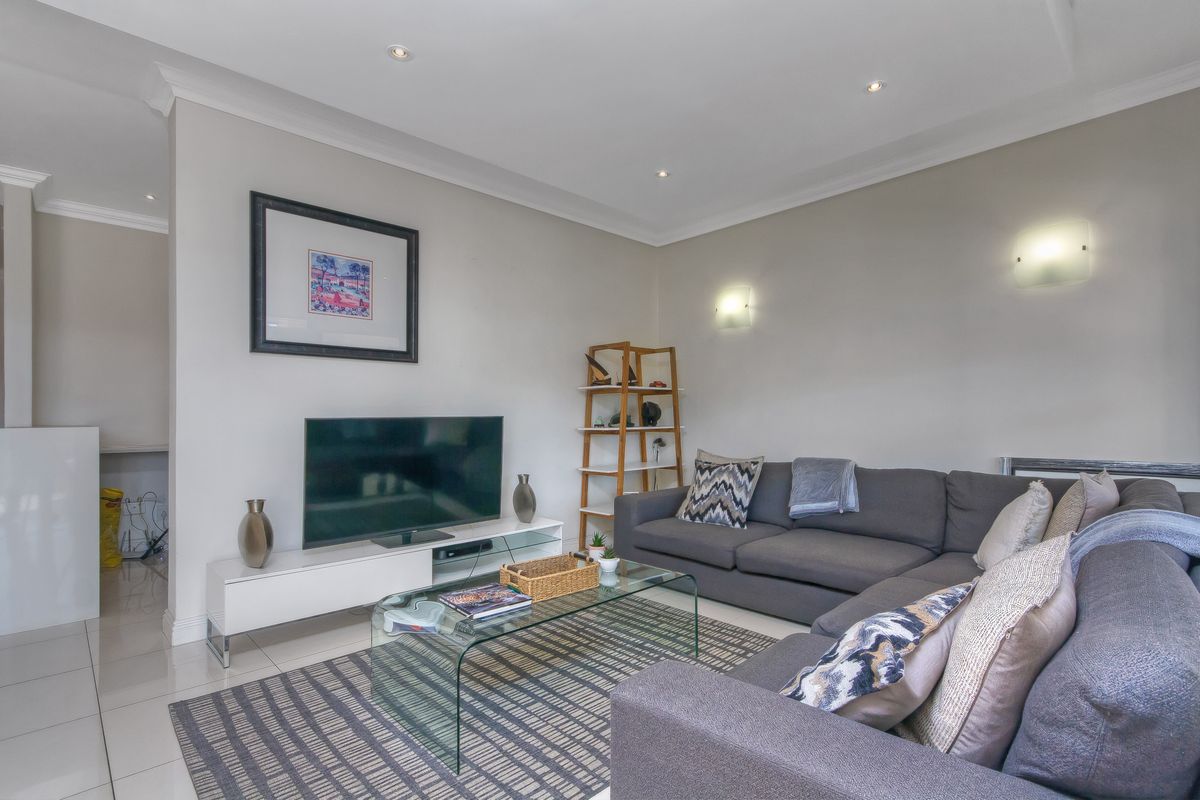 A well-maintained living room featuring neutral wall tones, recessed ceiling lighting, and polished floor tiles, creating a bright and comfortable living space.