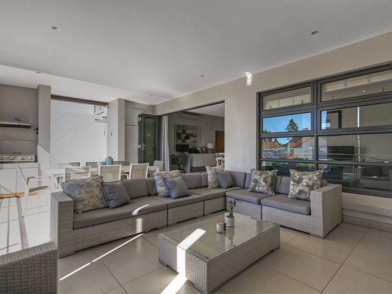 Spacious covered patio featuring tiled flooring, recessed lighting, and a built-in outdoor kitchen area, seamlessly connected to the interior through large stacking doors.