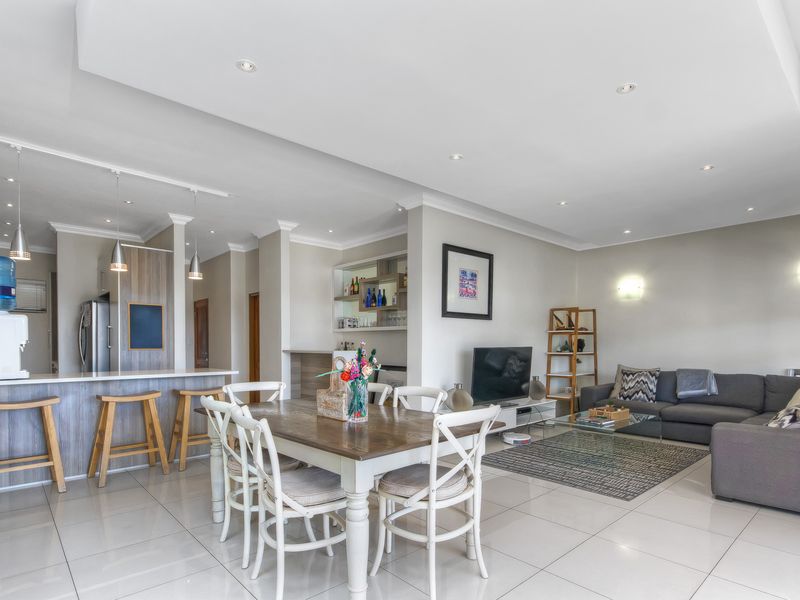 Spacious open-plan living area featuring tiled flooring, recessed ceiling lighting, and a functional kitchen breakfast bar with integrated cabinetry.