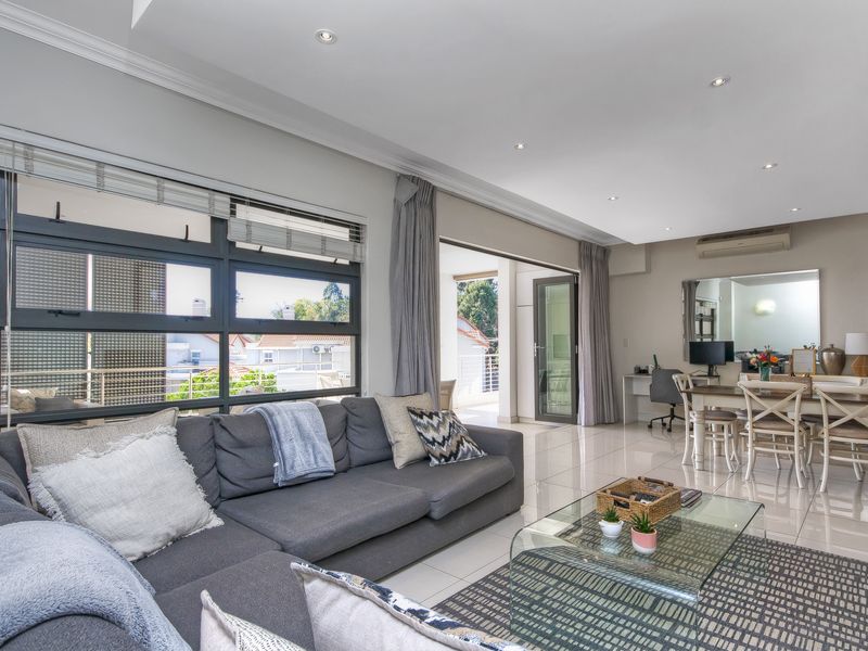Spacious open-plan living and dining area featuring tiled floors, recessed lighting, and large sliding doors leading to an outdoor balcony.