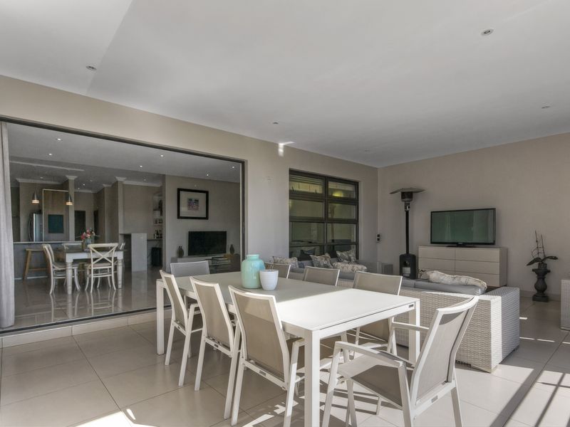 Spacious covered patio featuring large sliding glass doors that provide seamless indoor-outdoor flow, tiled flooring, and recessed ceiling lighting.