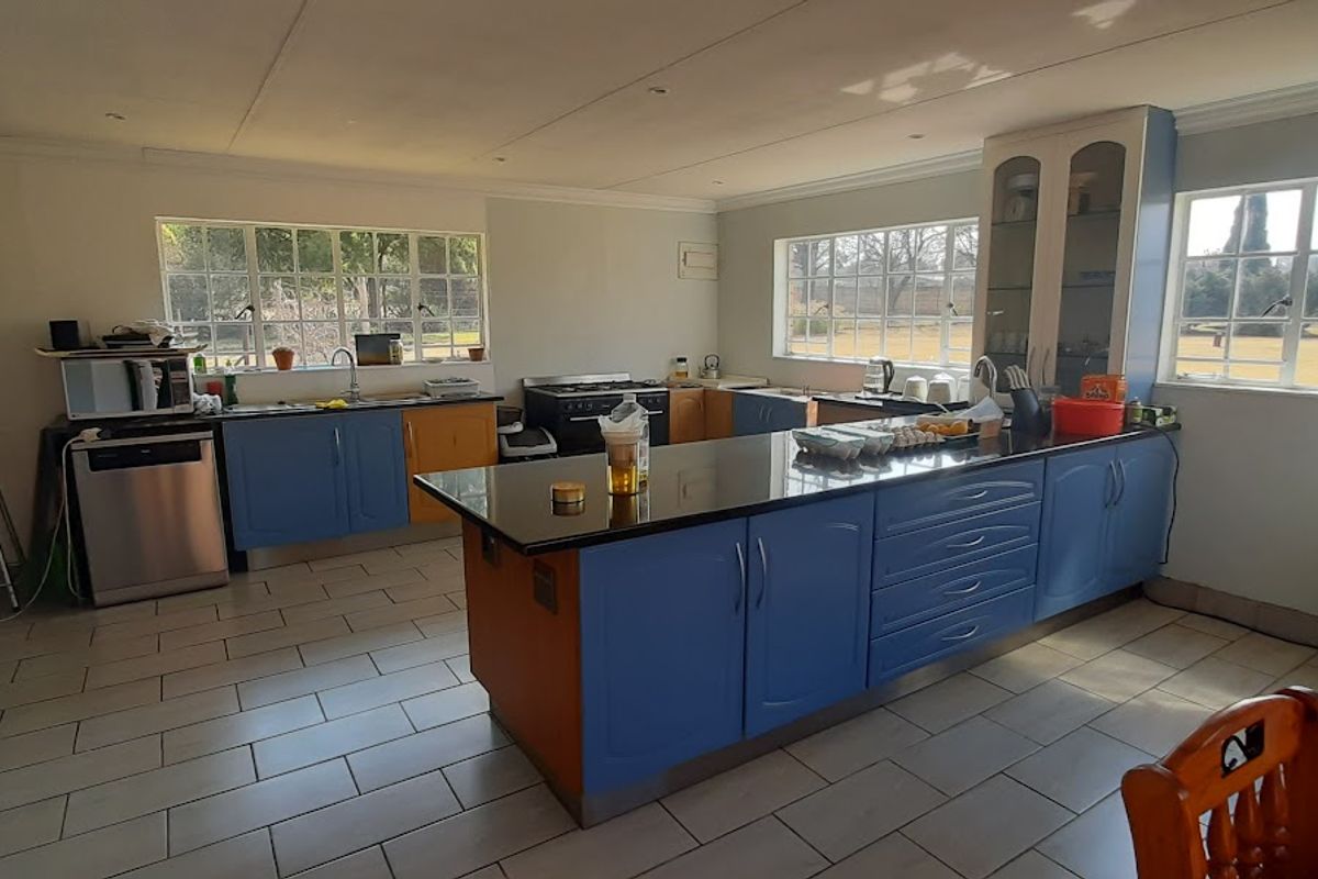 Spacious kitchen featuring a central island, granite countertops, blue cabinetry, and tiled flooring with ample natural light from multiple windows.