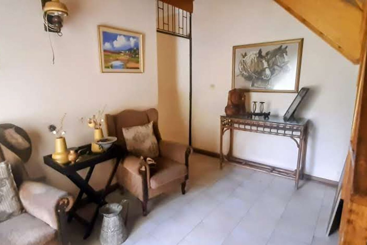 A living area featuring tiled flooring and a wooden staircase leading to an upper level.
