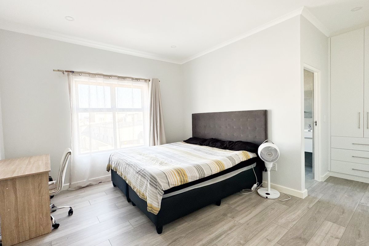 A bright and well-maintained bedroom featuring built-in floor-to-ceiling cabinetry and modern wood-look tile flooring.