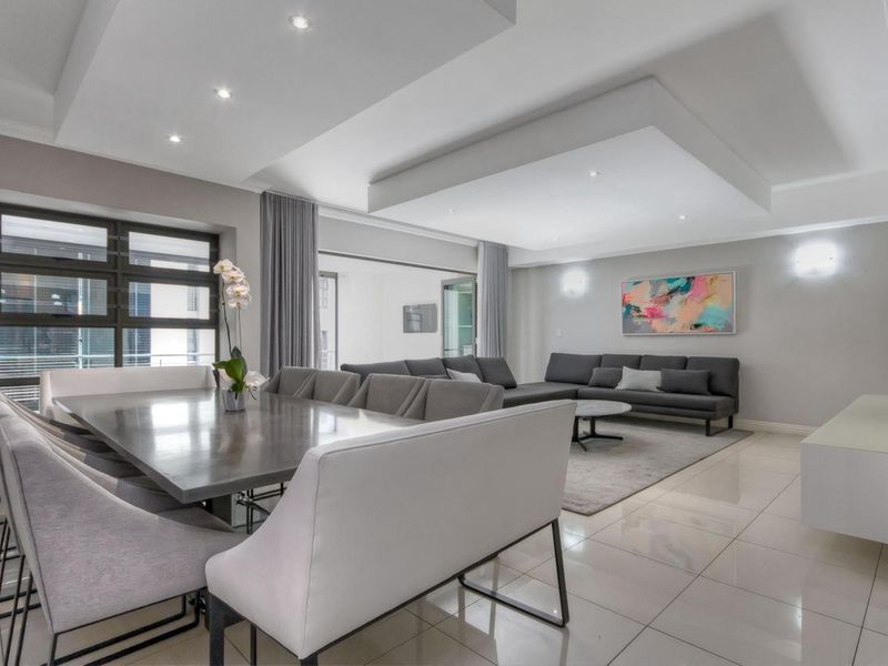 Spacious open-plan living and dining area featuring modern recessed ceilings, downlights, and polished tiled flooring with seamless access to the balcony.