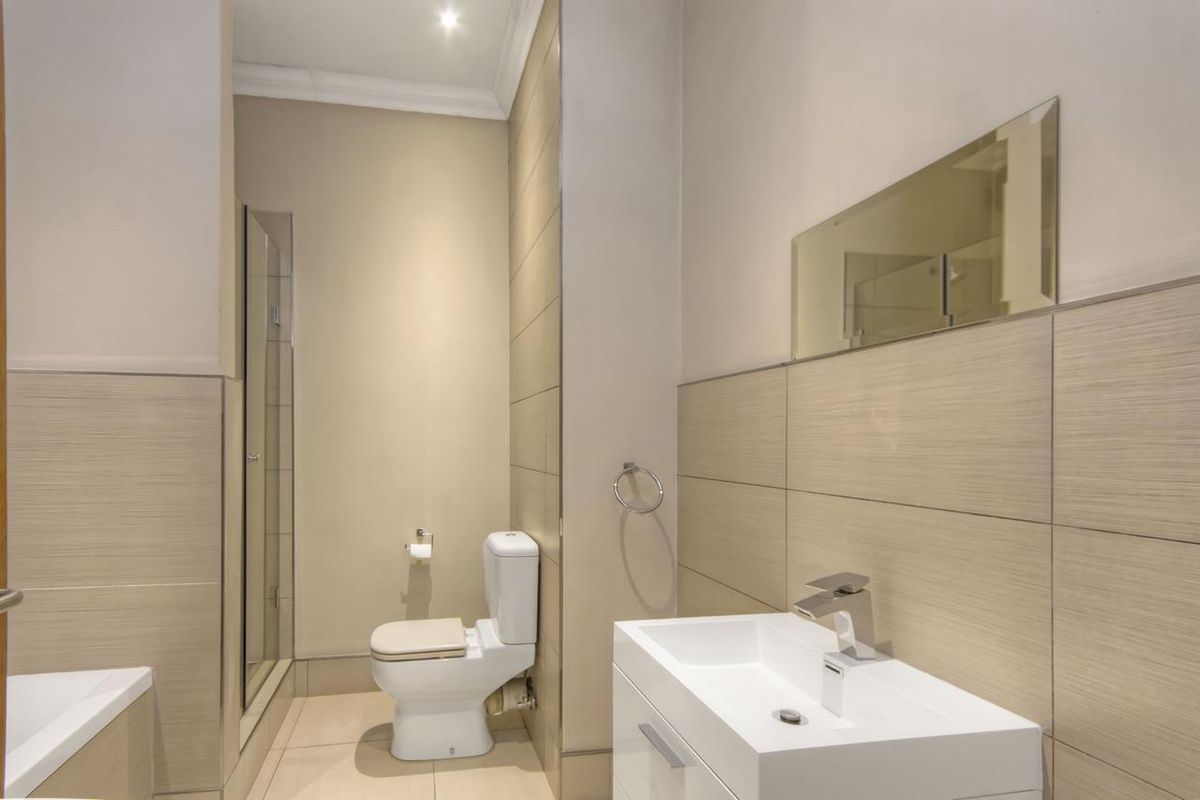 Modern bathroom featuring a sleek vanity with basin, a separate shower enclosure, and neutral wall and floor tiling.