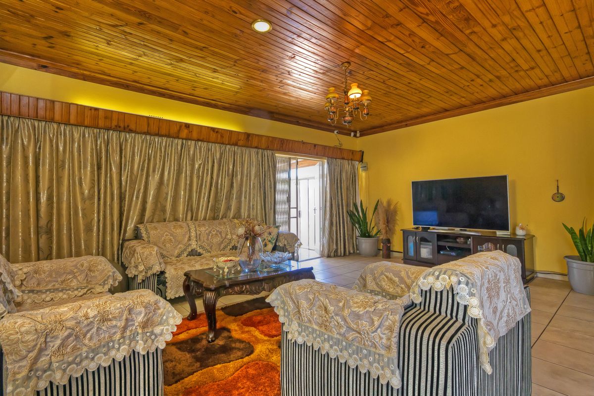Spacious living room featuring a warm timber tongue and groove ceiling, tiled flooring, and direct access to the outdoor area via a sliding glass door.