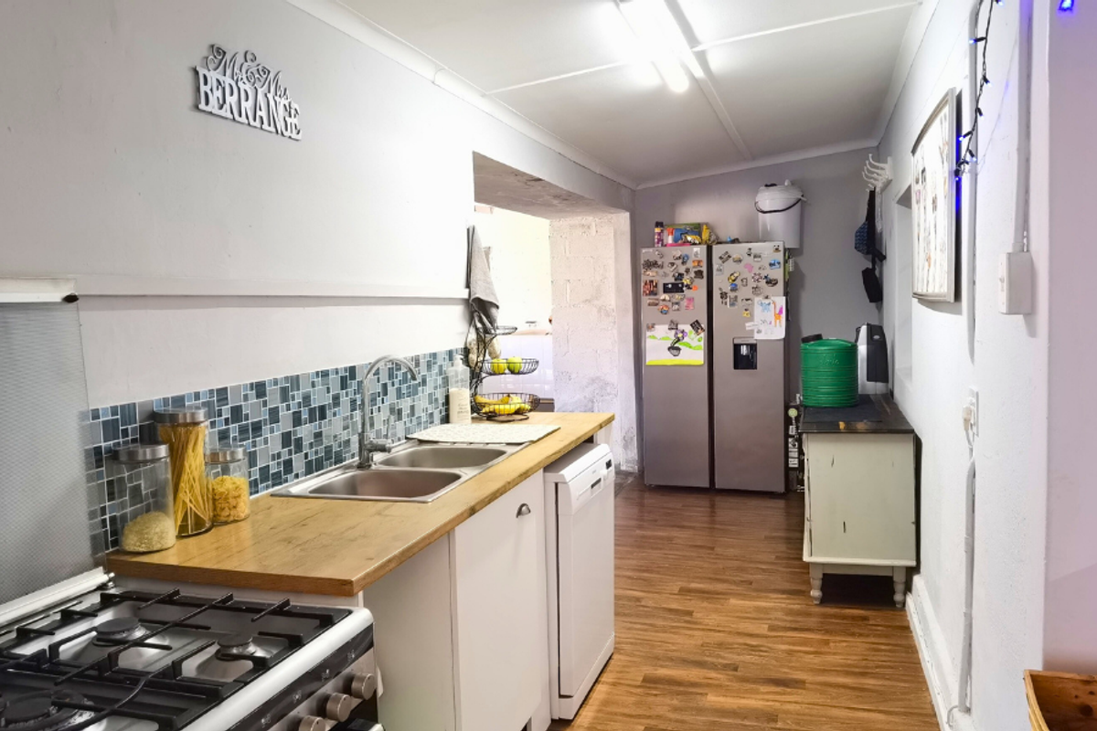 A functional kitchen featuring a double sink, wood-look countertops, mosaic tile backsplash, and a gas hob, with an adjacent utility area.