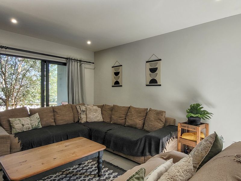 A bright living room featuring tiled flooring, recessed downlights, and a large sliding glass door providing access to the outdoor area.