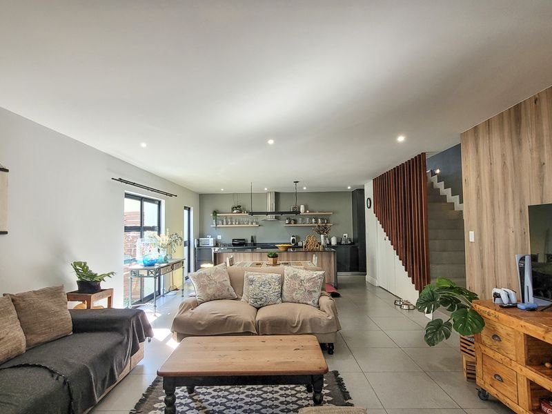 Spacious open-plan living and kitchen area featuring modern tiled floors, a timber slat staircase feature, and a contemporary kitchen with an island.