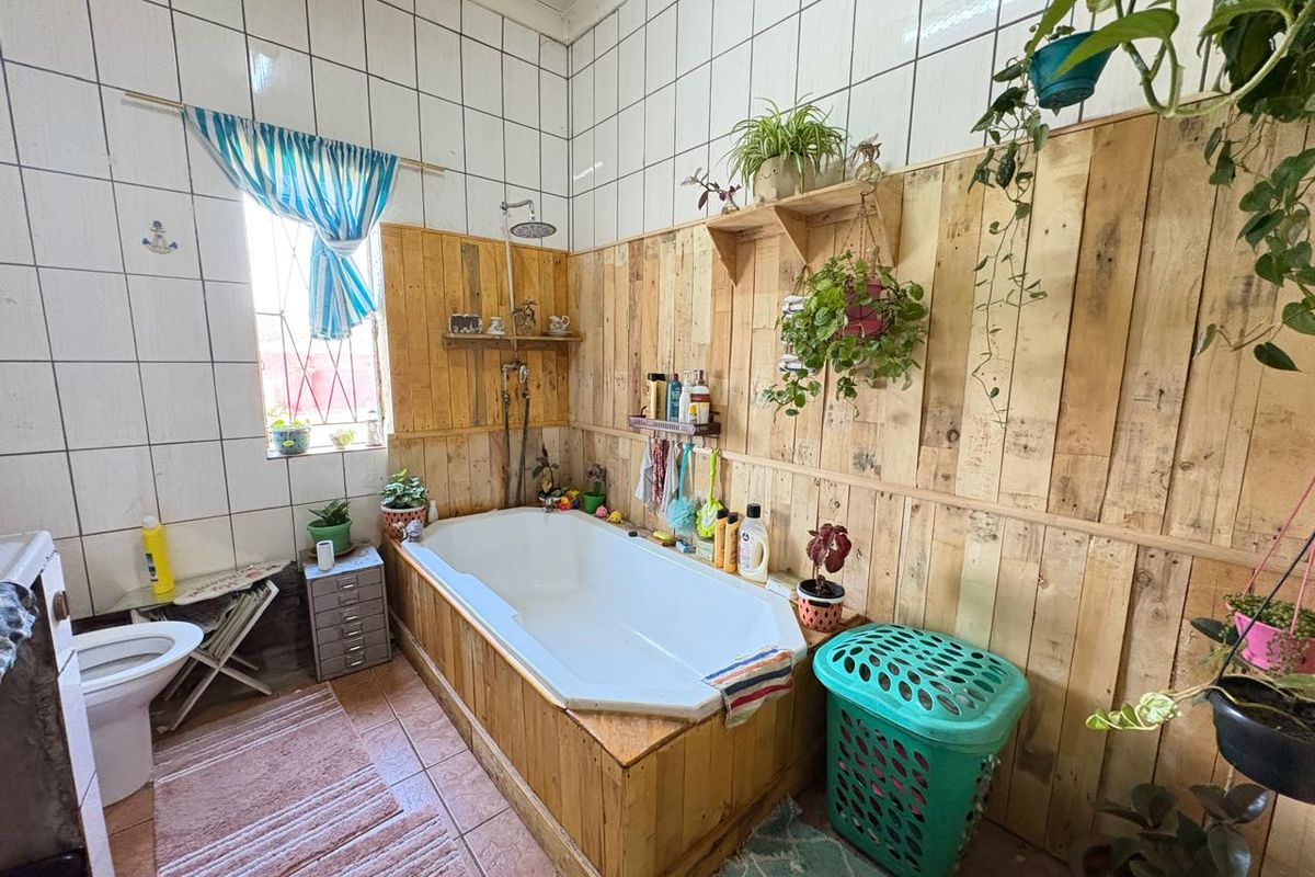 Bathroom featuring a built-in bathtub with shower head, tiled walls, and timber wall cladding. The space requires cosmetic updates to modernize the finishes.