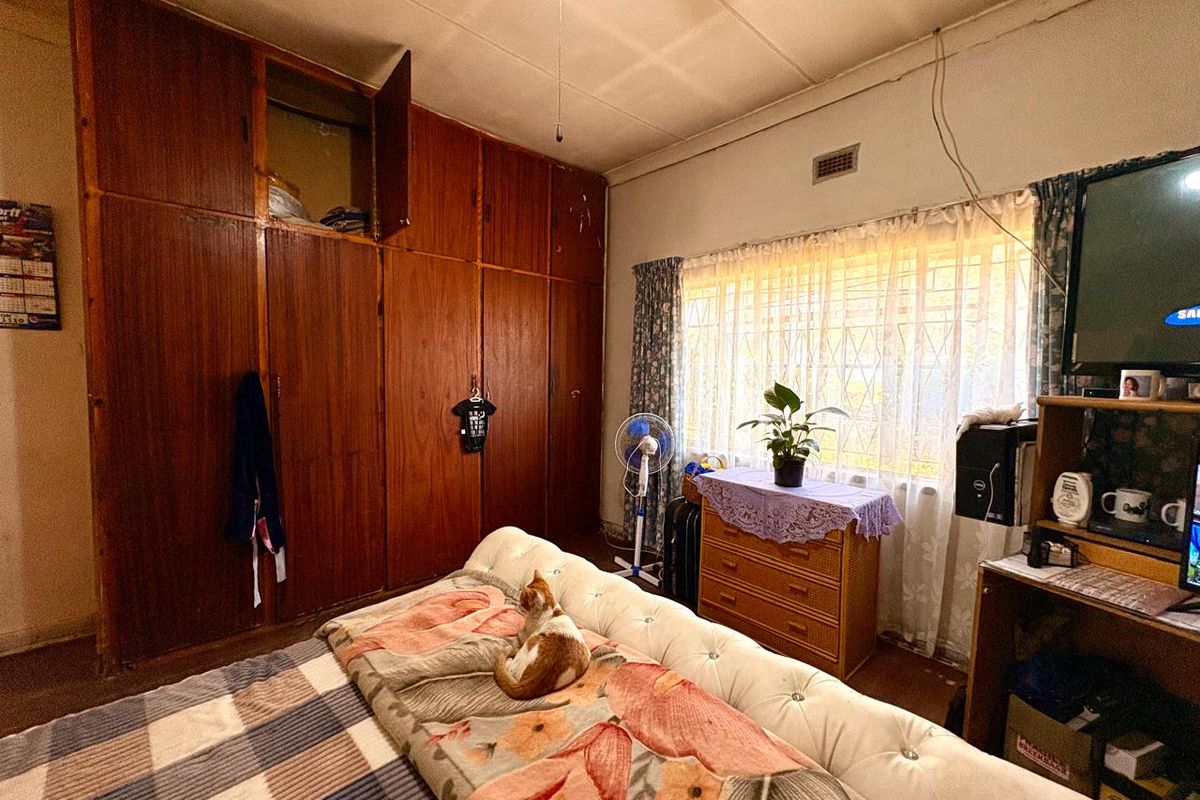 Bedroom featuring floor-to-ceiling built-in wooden cupboards, a ceiling fan, and security bars on the window.