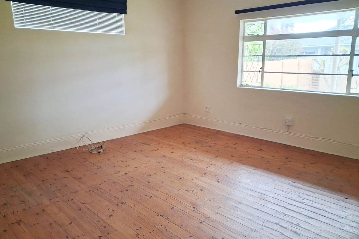 An empty bedroom featuring original timber flooring, steel-framed windows, and neutral wall finishes, offering a blank canvas for potential interior design updates.