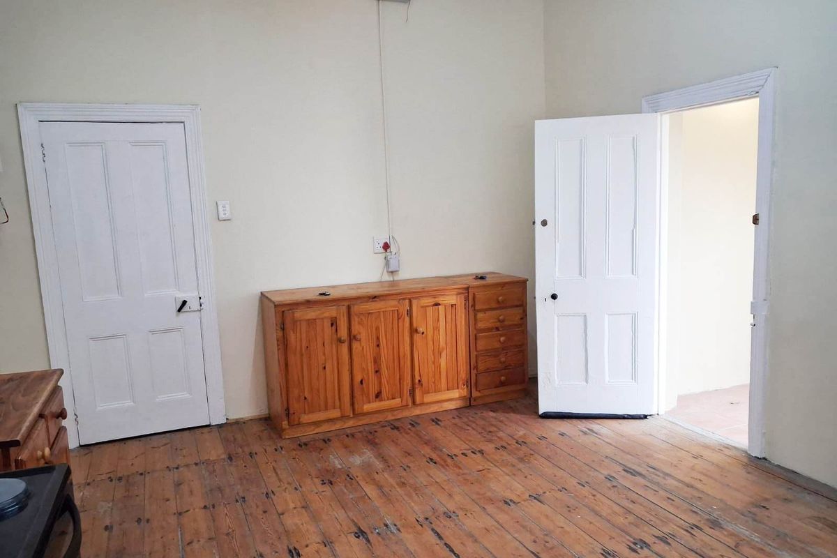 An empty bedroom featuring original timber flooring and classic panel doors, offering a blank canvas for renovation or interior design updates.