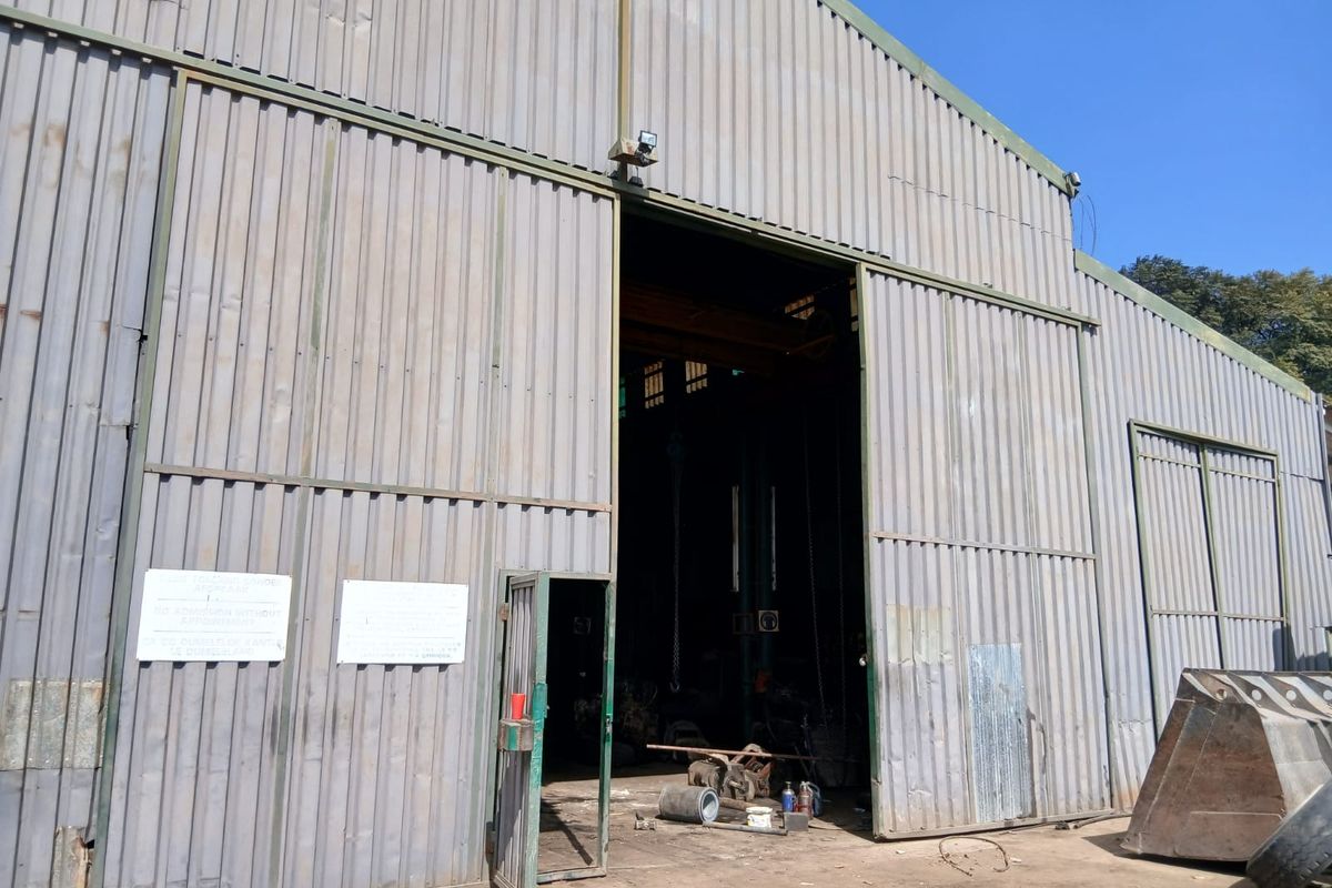 Industrial utility shed featuring large sliding metal doors, corrugated steel cladding, and an internal overhead crane rail system.