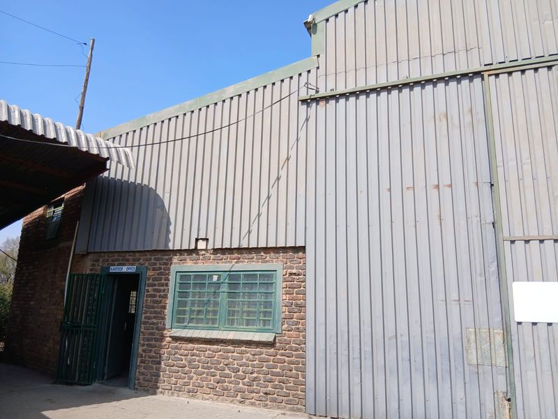 Exterior view of a small holding industrial-style building featuring corrugated metal cladding, face brick walls, and a dedicated office entrance.
