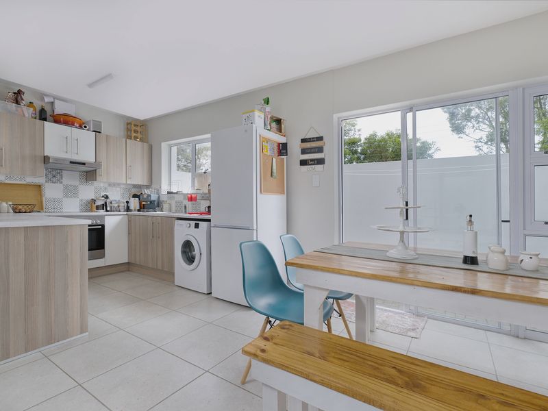 Open-plan kitchen and dining area featuring modern cabinetry, tiled flooring, and large sliding glass doors providing access to the outdoor space.