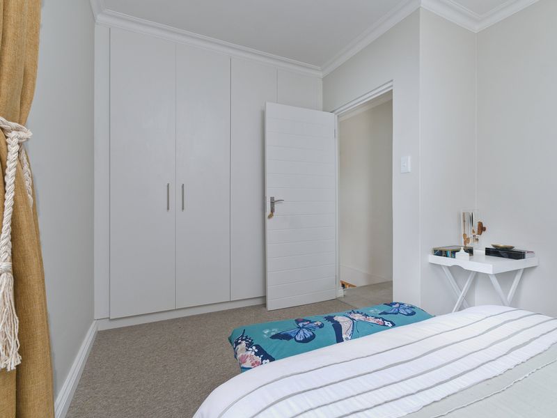 A well-maintained bedroom featuring neutral wall tones, carpeted flooring, and ample built-in cupboard storage.