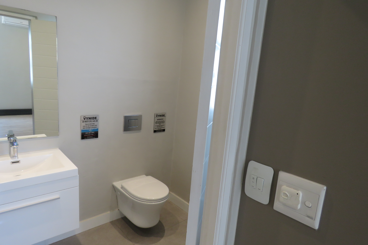 Modern bathroom featuring a wall-mounted toilet, floating vanity with integrated basin, and a large wall mirror.
