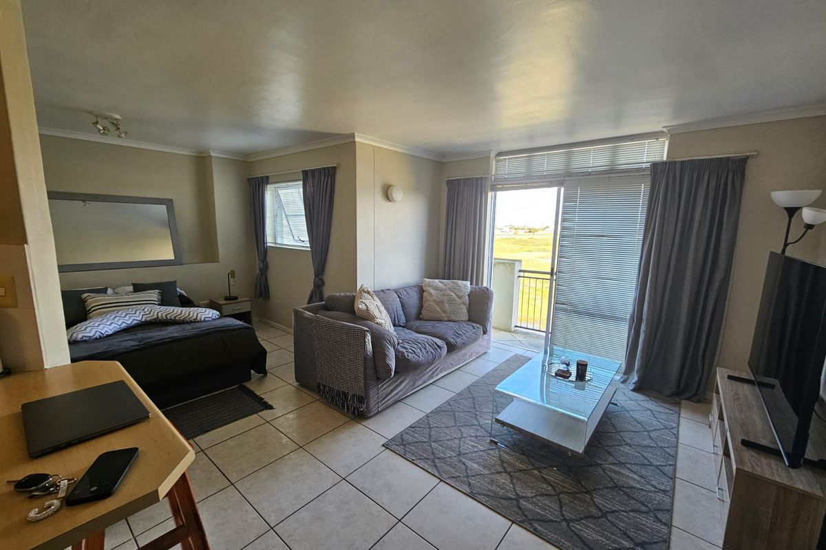 Open-plan living area featuring tiled flooring and a sliding glass door leading to a balcony with natural light.