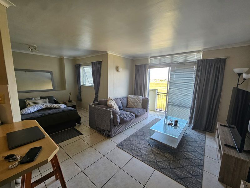 Open-plan living area featuring tiled flooring and a sliding glass door leading to a balcony with natural light.