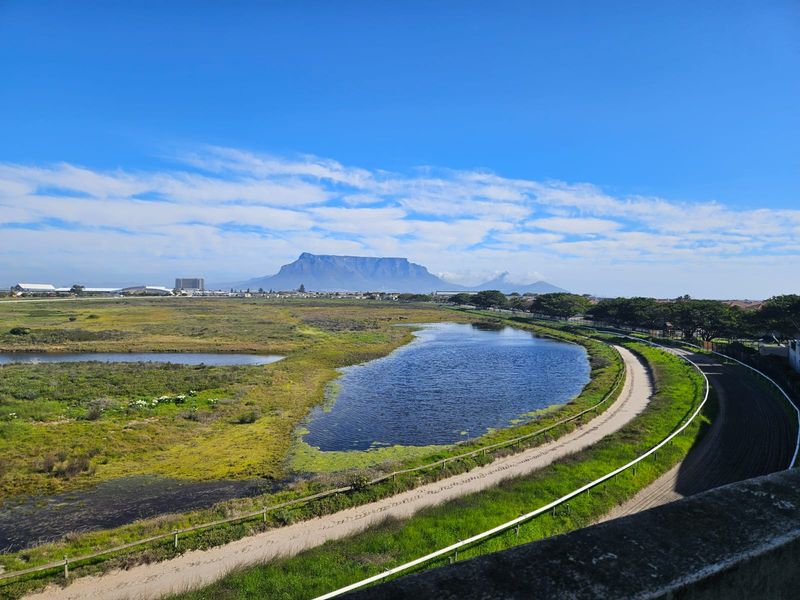 A scenic outdoor view featuring a natural landscape, a small lake, and a distant mountain range under a clear blue sky.