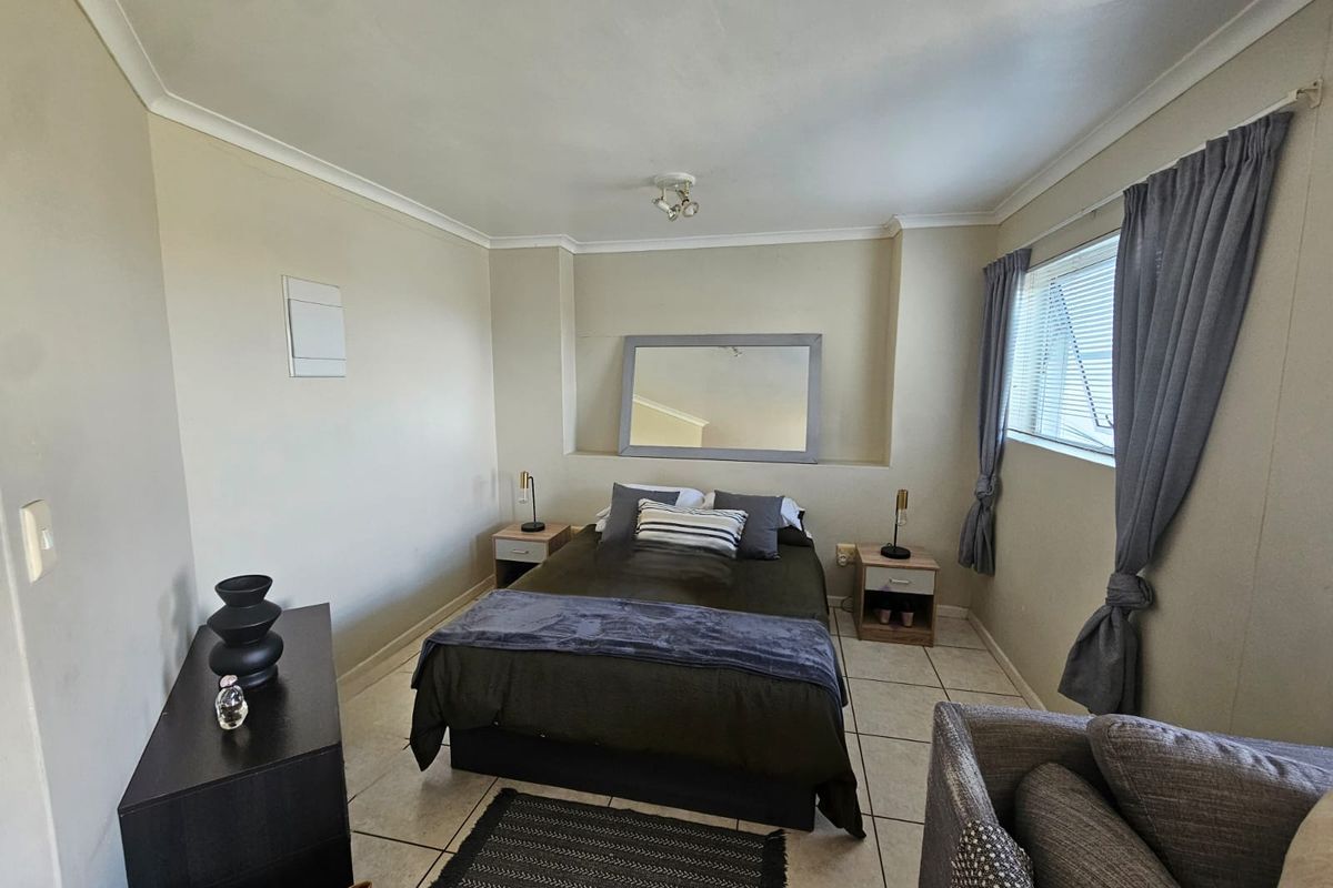 A functional bedroom featuring tiled flooring, coved ceilings, and a window with curtain tracks, providing a neutral base for personalization.