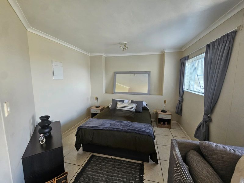 A functional bedroom featuring tiled flooring, coved ceilings, and a window with curtain tracks, providing a neutral base for personalization.