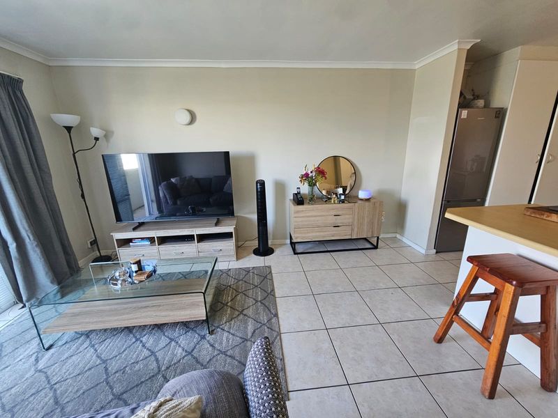 Open plan living area featuring tiled flooring and a breakfast bar, creating a functional and connected space for relaxation and dining.