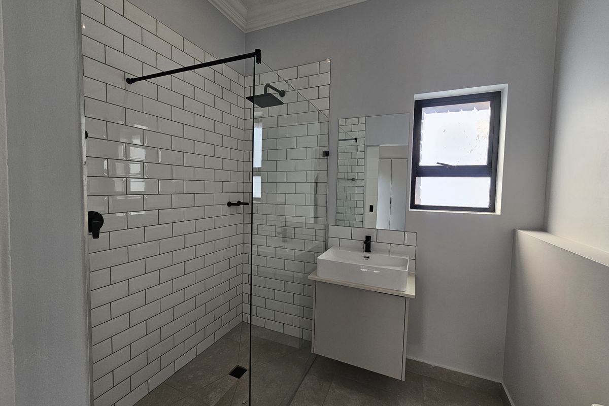 Modern bathroom featuring a walk-in shower with subway tile surround, a floating vanity with basin, and contemporary black fixtures.
