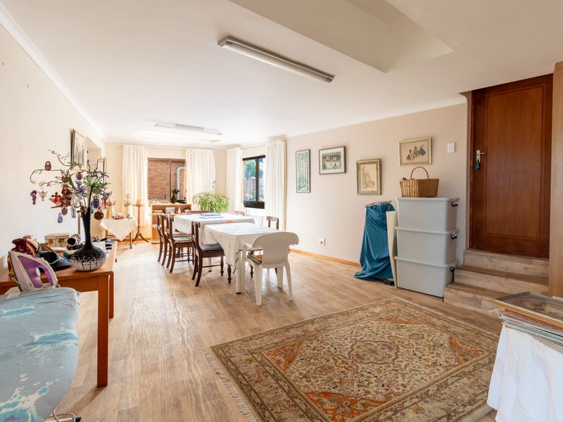 Spacious living area featuring light-toned laminate flooring, neutral walls, and a raised doorway leading to an adjacent section of the home.