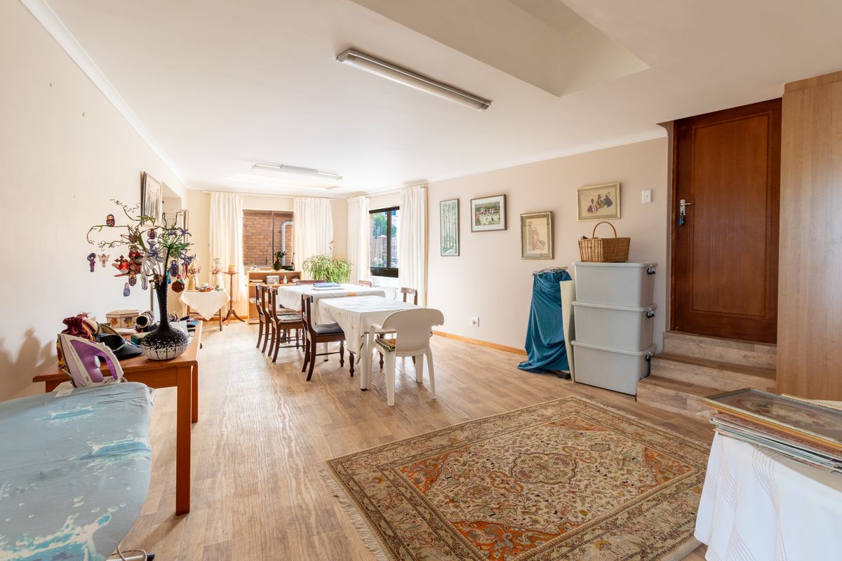 Spacious living area featuring light-toned laminate flooring, neutral walls, and a raised doorway leading to an adjacent section of the home.