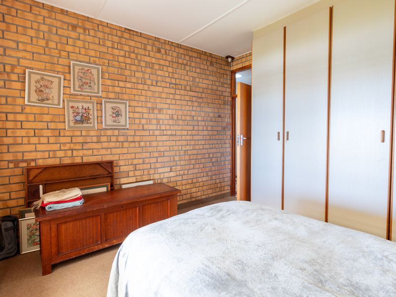 A bedroom featuring an exposed brick feature wall and floor-to-ceiling built-in cupboards, offering a classic aesthetic with potential for modern updates.