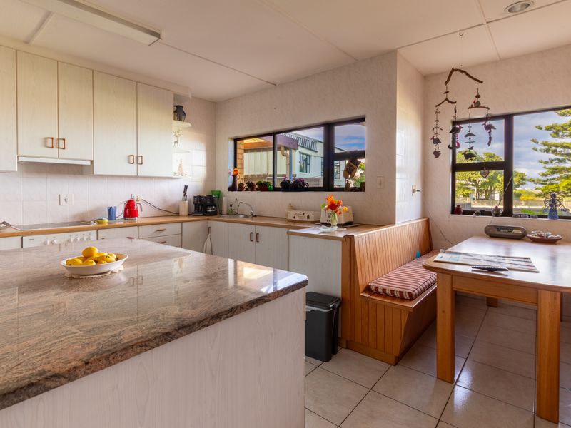 A functional kitchen featuring granite countertops, ample built-in cabinetry, and a cozy integrated breakfast nook with natural light.