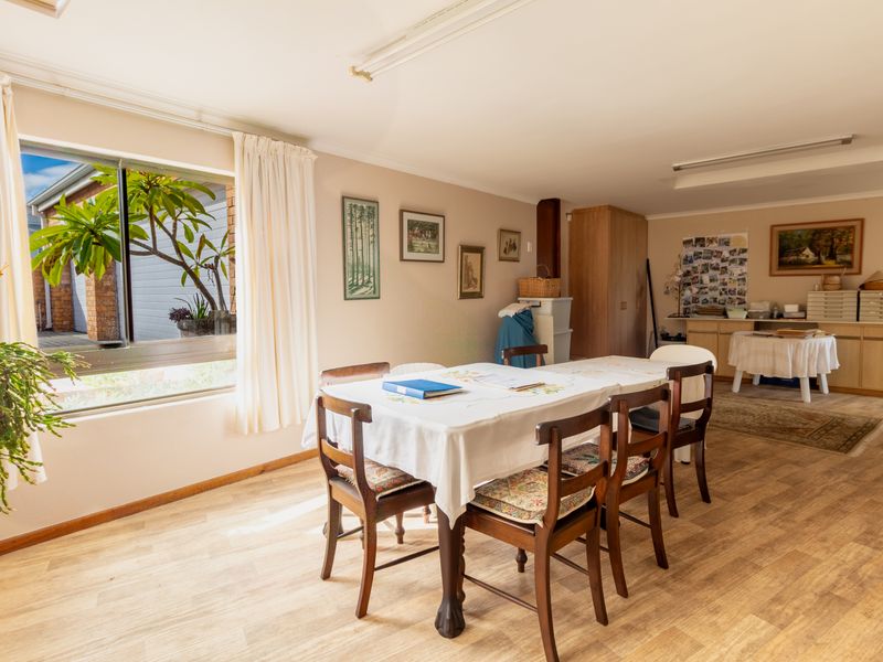 A spacious dining area featuring wood-look flooring, large sliding windows, and built-in cabinetry, offering a functional and versatile living space.