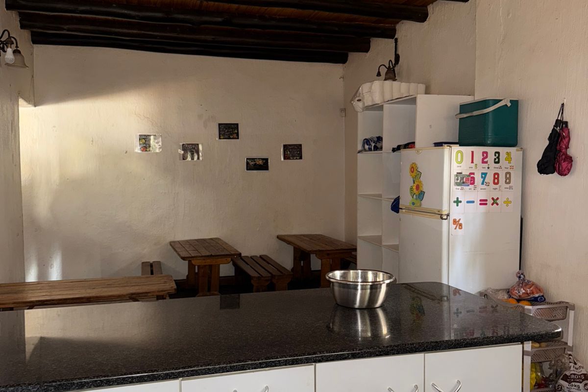 A functional kitchen area featuring a granite countertop, white cabinetry, and a rustic exposed timber beam ceiling.