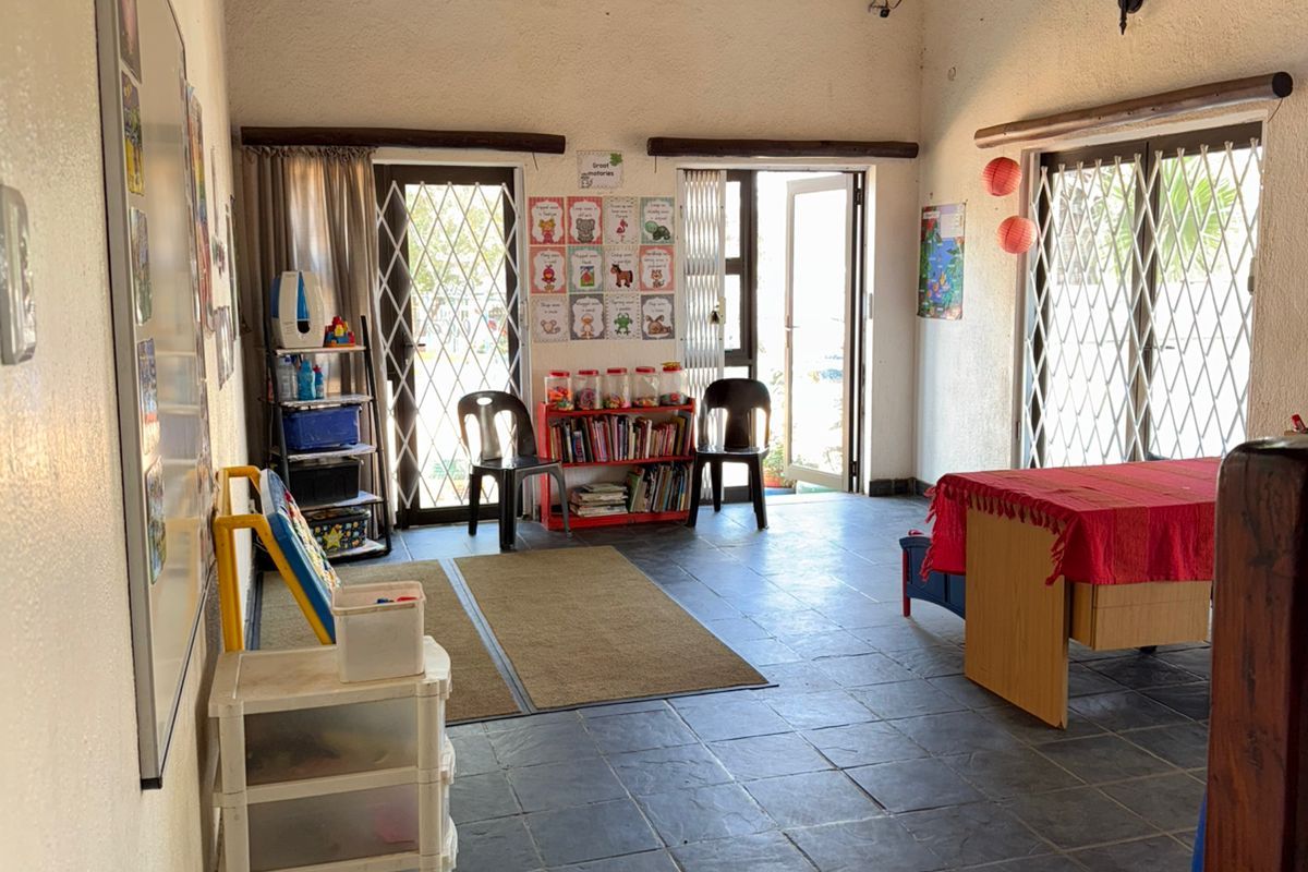 Spacious living area featuring a high thatched ceiling, exposed timber beams, and durable slate tile flooring with access to the exterior via security gates.