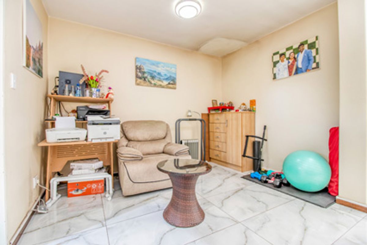 A multi-purpose room featuring large format marble-look floor tiles and a central ceiling light fixture.