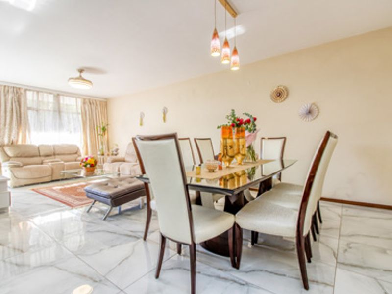 Spacious open-plan living and dining area featuring polished marble-look floor tiles and modern pendant lighting.