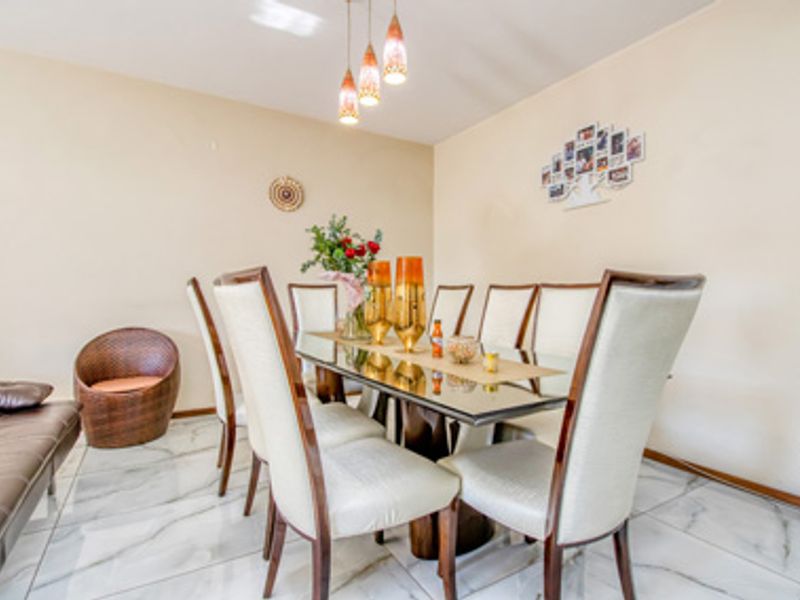 A dining area featuring polished marble-look floor tiles and a modern pendant light fixture, creating a bright and functional space for meals.