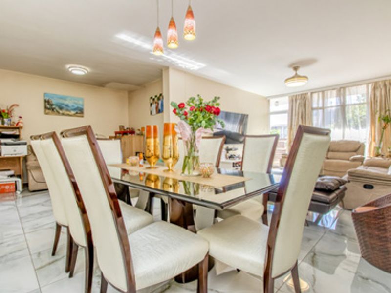 Open plan living and dining area featuring polished marble-look floor tiles and large windows allowing for natural light.