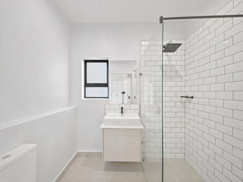 Modern bathroom featuring a floating vanity, walk-in shower with glass screen, and clean white subway tiling.
